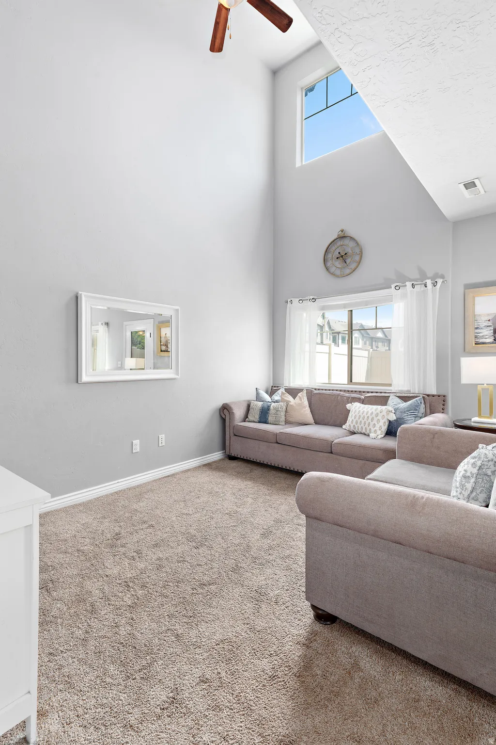 Living area featuring vaulted ceilings, a ceiling fan, plush carpet flooring, and upper transom windows