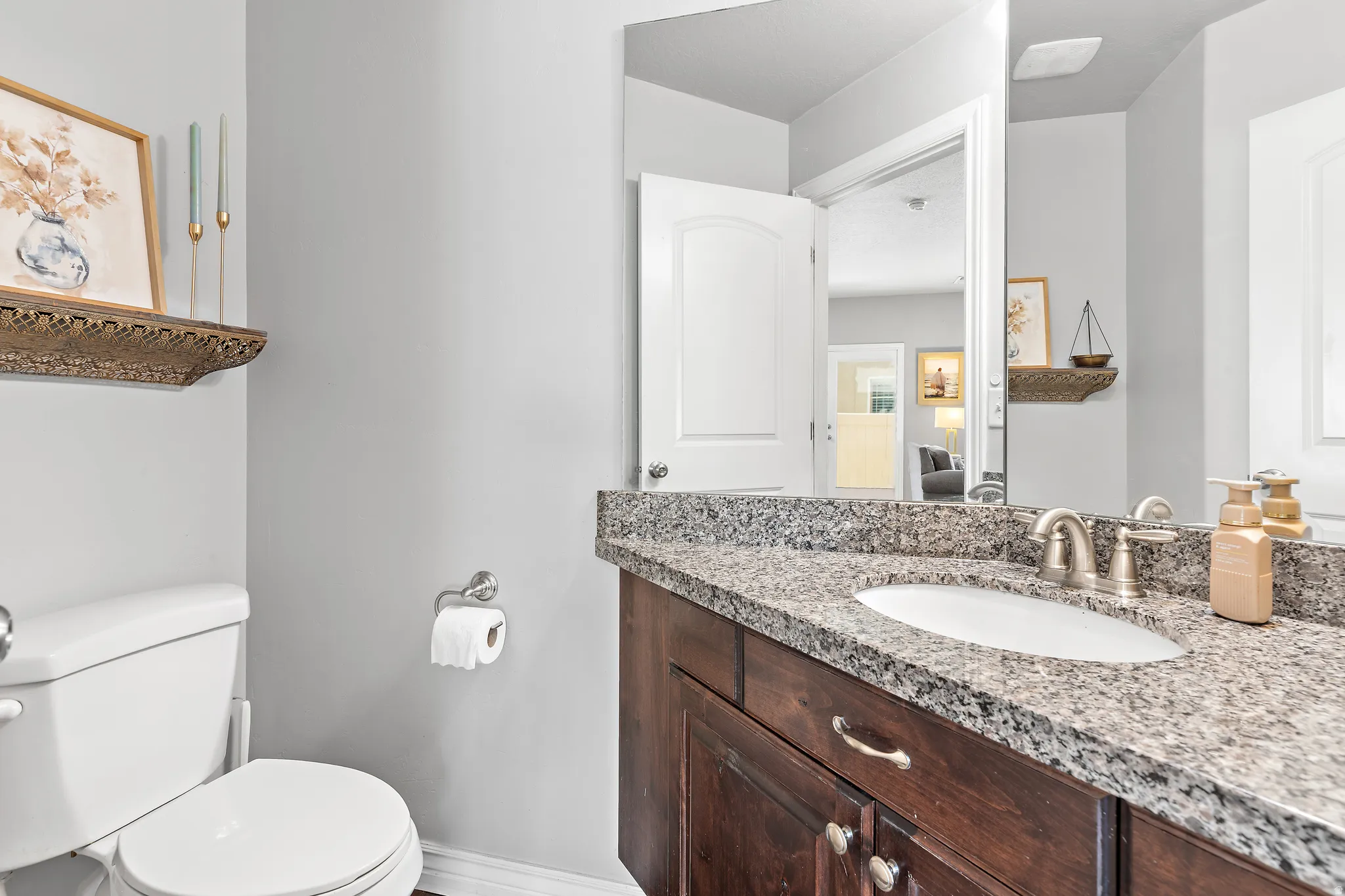 Vanity featuring a dark wood-finish cabinet, a light-toned granite countertop, and an undermount sink with a brushed nickel faucet