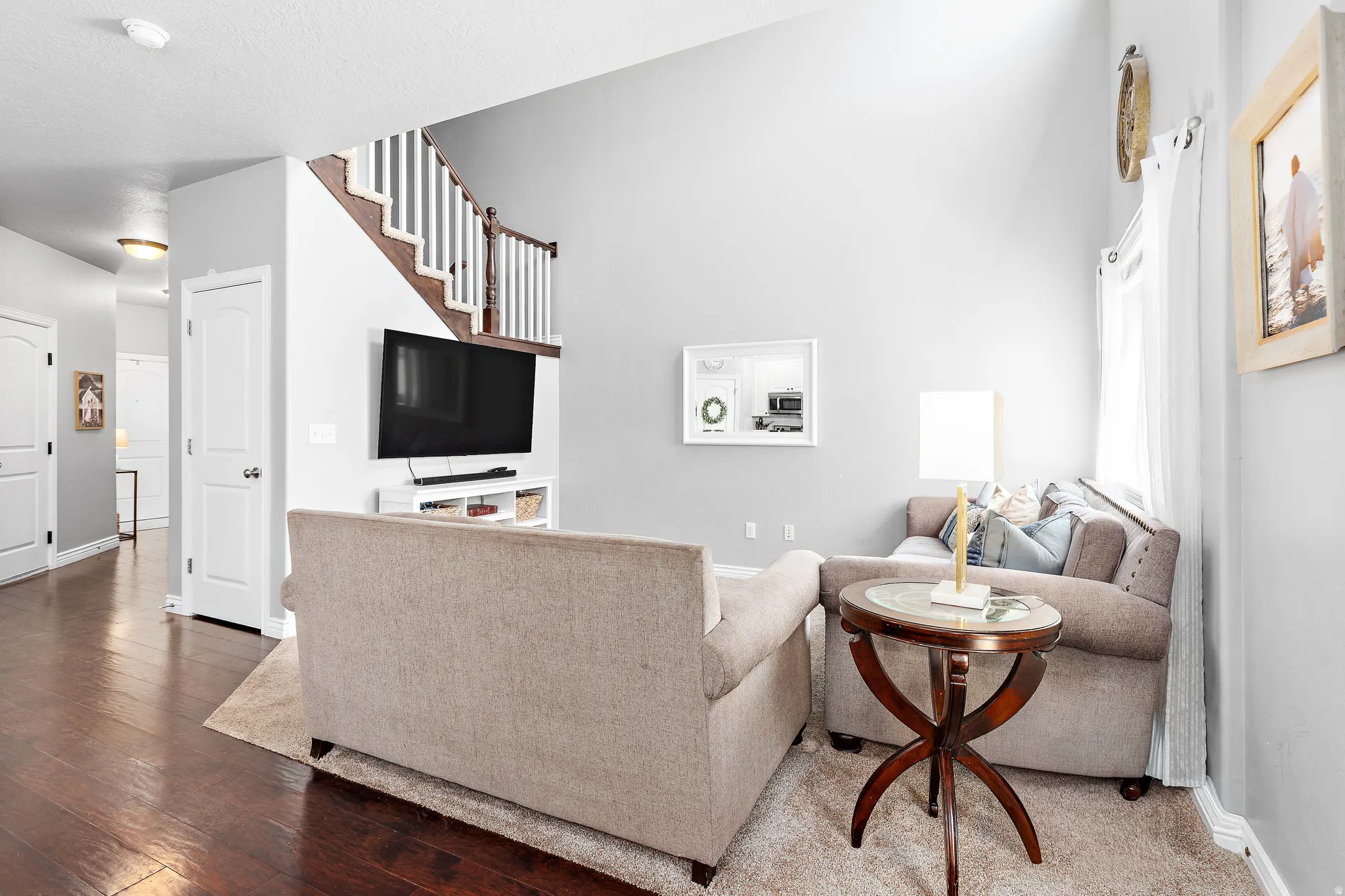 Living area featuring vaulted ceilings, wood-finish flooring, a contemporary staircase with white risers and wood treads, and white interior doors