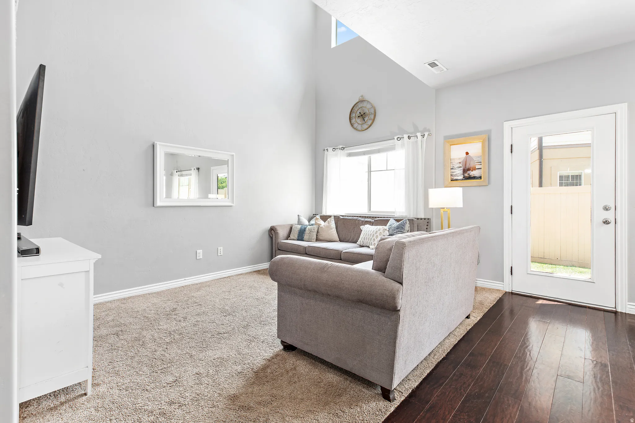 Living area featuring a high vaulted ceiling, large windows, and a glass-paneled exterior door