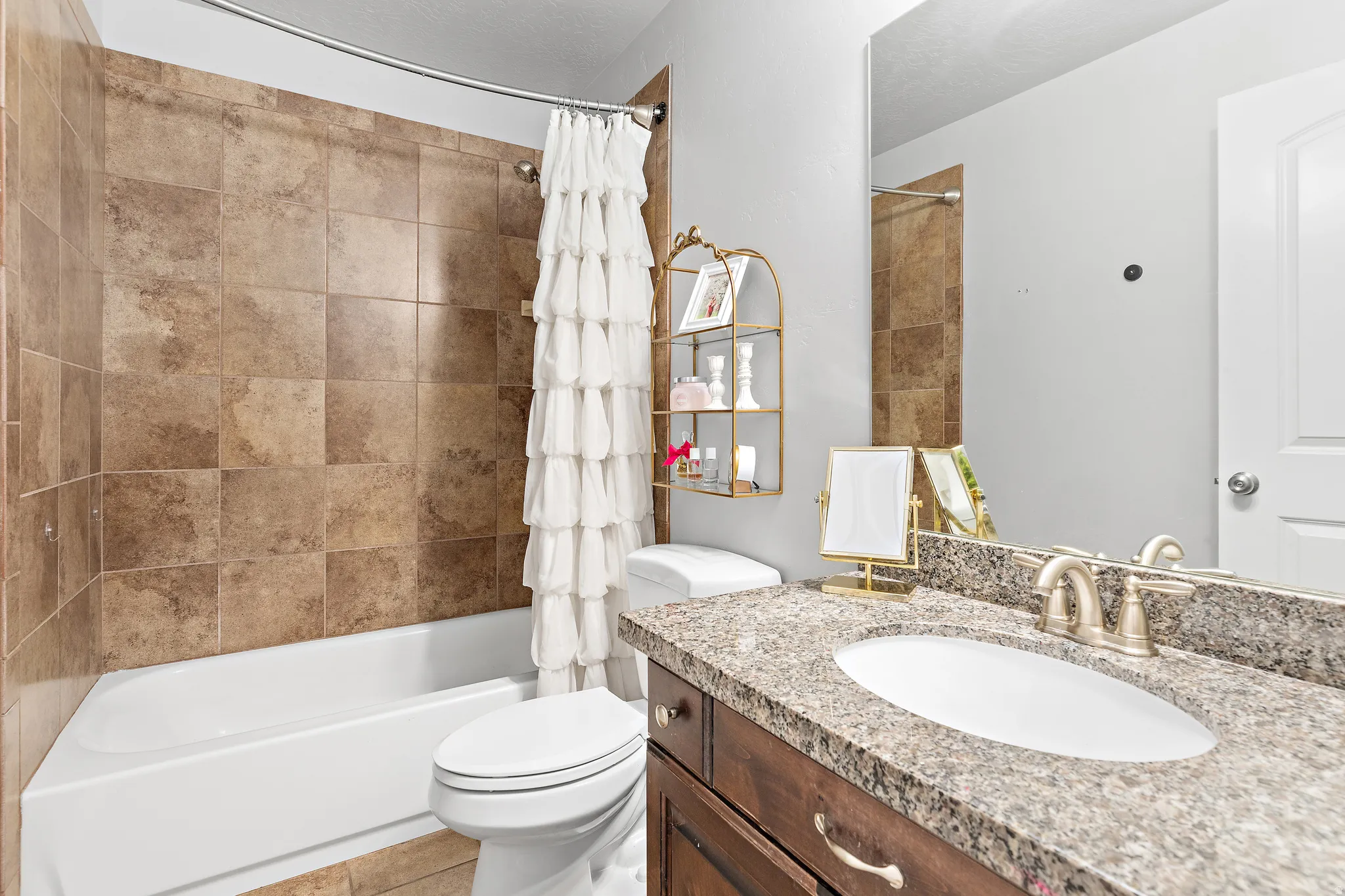 Bathroom featuring a tub/shower combination with tile surround, a vanity with a stone countertop, an undermount sink, and a large wall-mounted mirror
