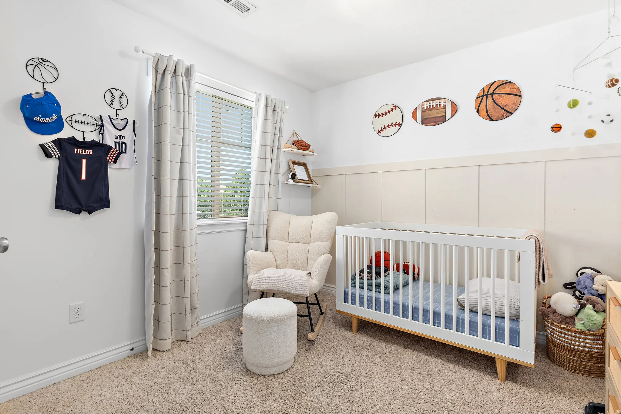 Bright room featuring a window with blinds, board and batten wall detailing, and light-toned carpeting