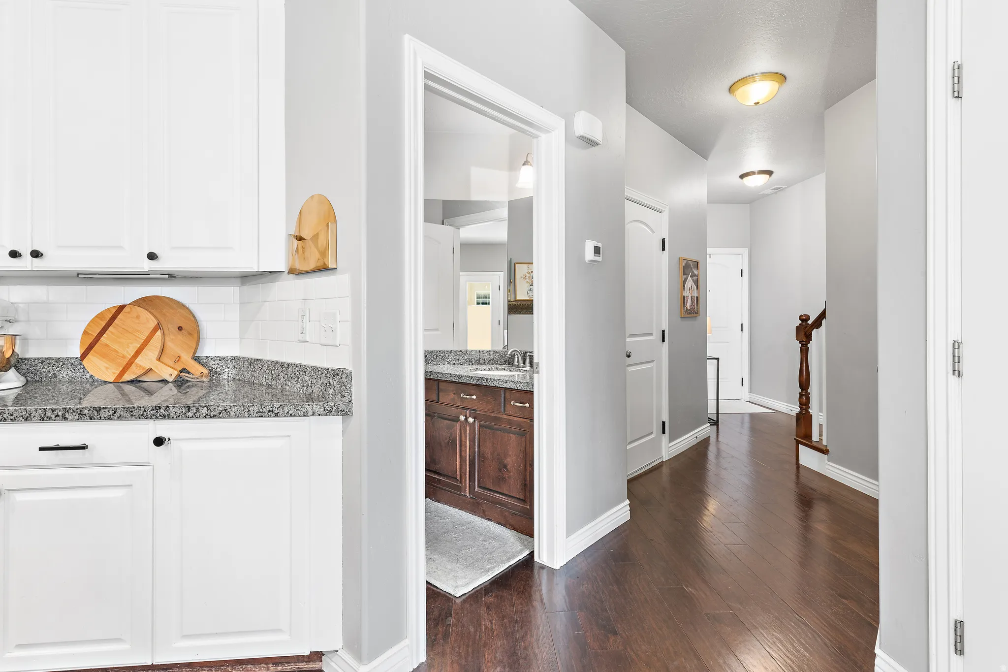 Hallway with wood-finish flooring, white baseboards, and overhead lighting