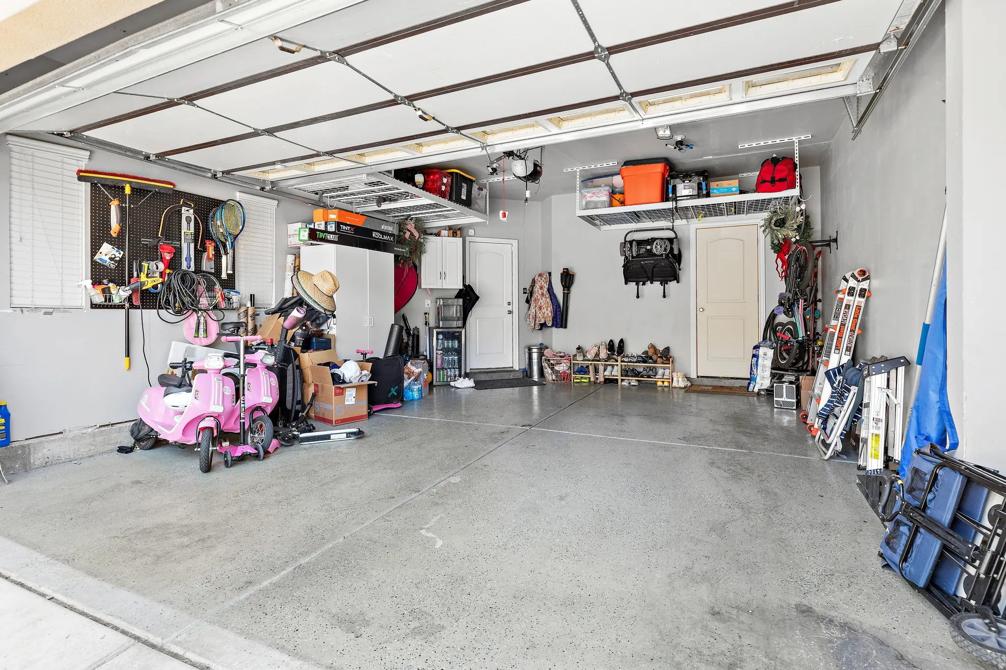 Two-car garage featuring a concrete floor, overhead storage racks, and wall-mounted organization systems