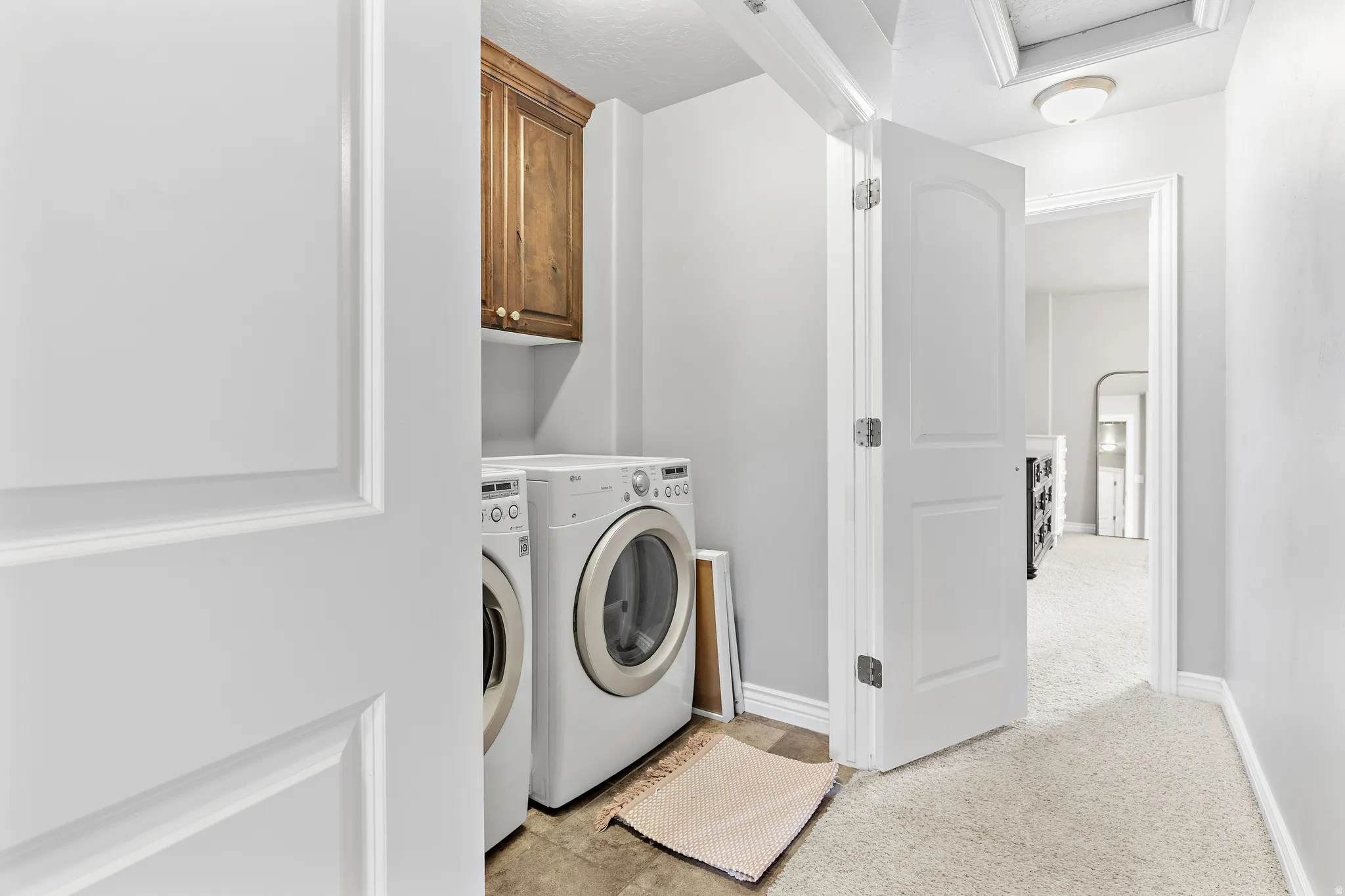 Dedicated laundry area with upper wood cabinetry and tile flooring