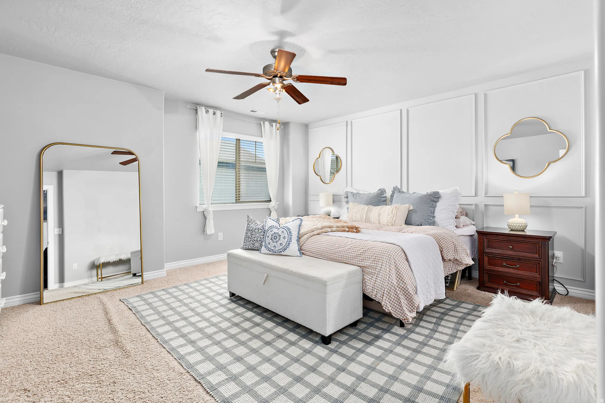 Bedroom featuring a paneled accent wall, a ceiling fan with integrated lighting, window with blinds, and neutral-toned carpeting