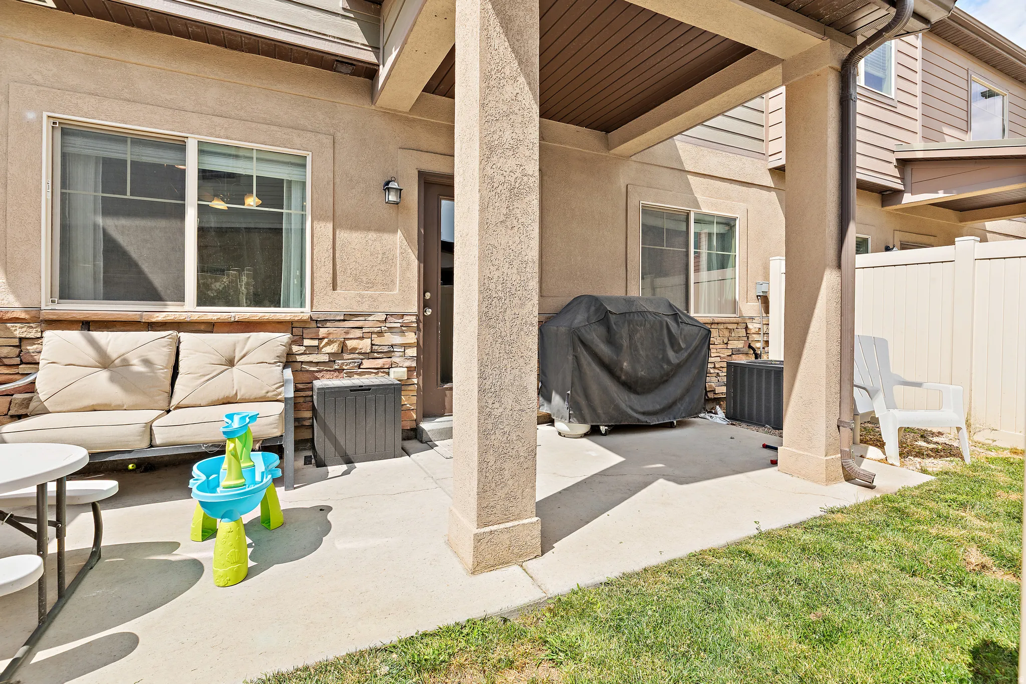 Concrete patio with a partial overhang, complemented by a stucco exterior and stone veneer accents