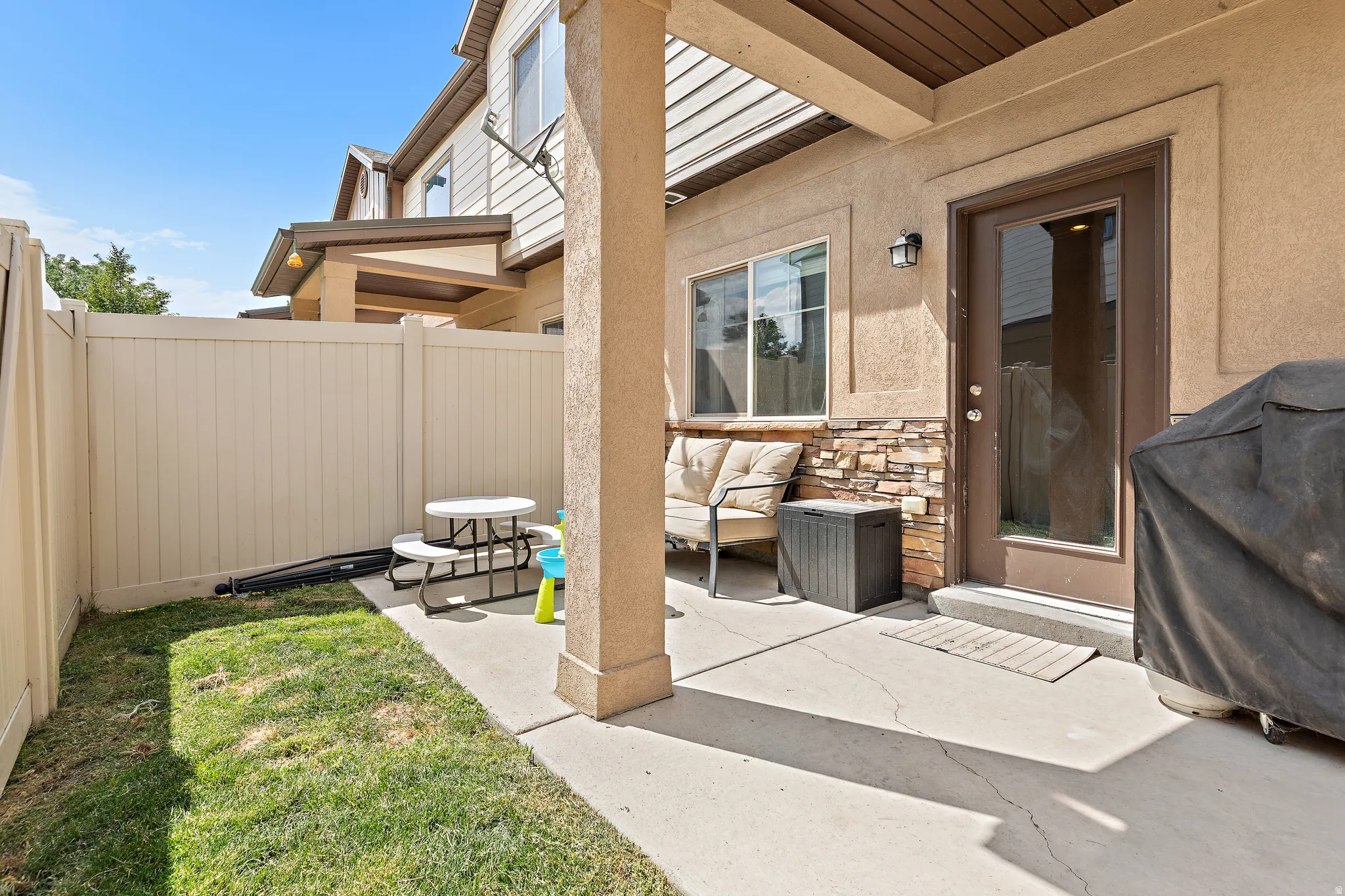 Private fenced patio featuring a concrete slab, small grass area, and exterior door with a full-light panel