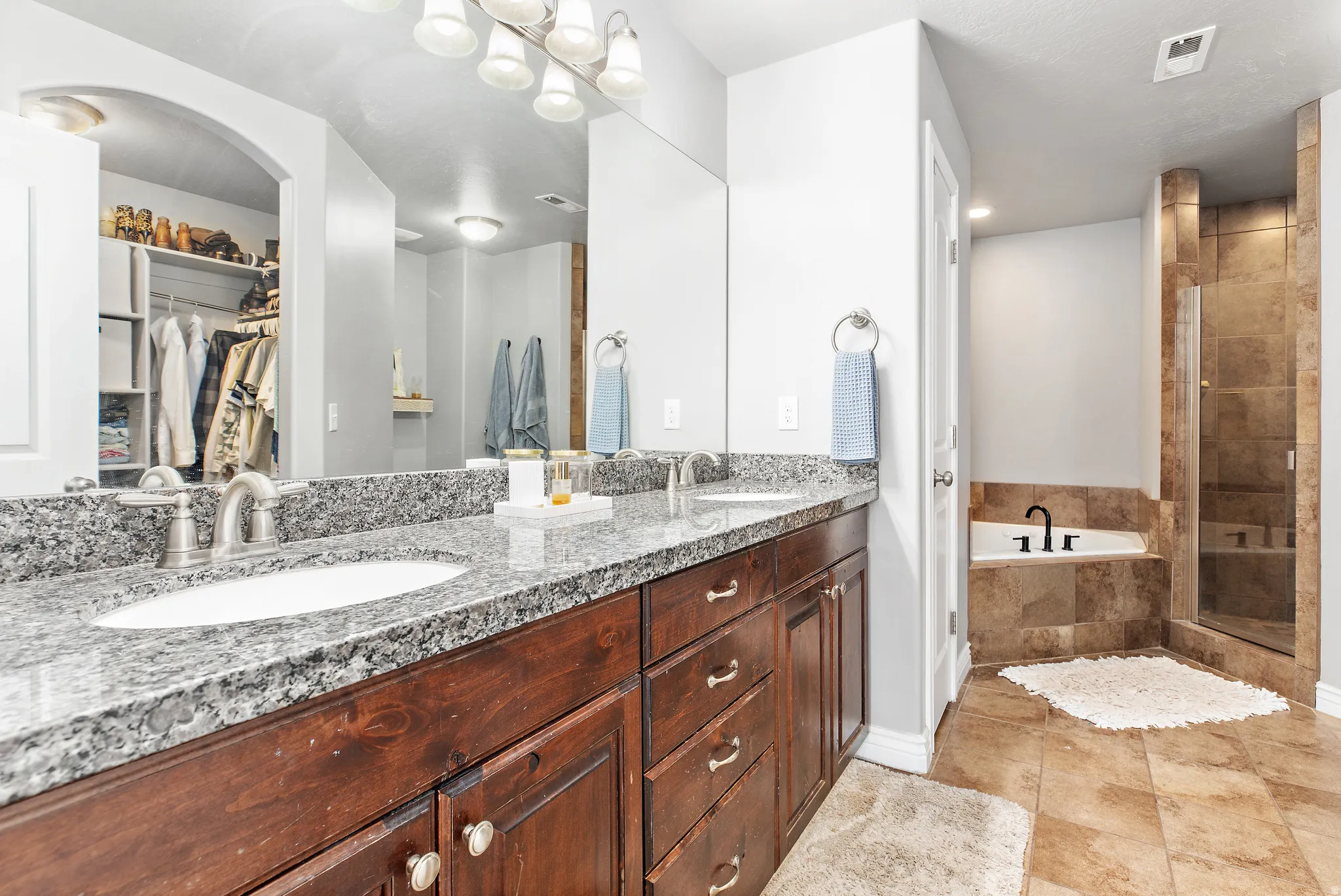 Bathroom featuring a dual vanity with granite countertops, wood-finish cabinetry, and brushed nickel hardware