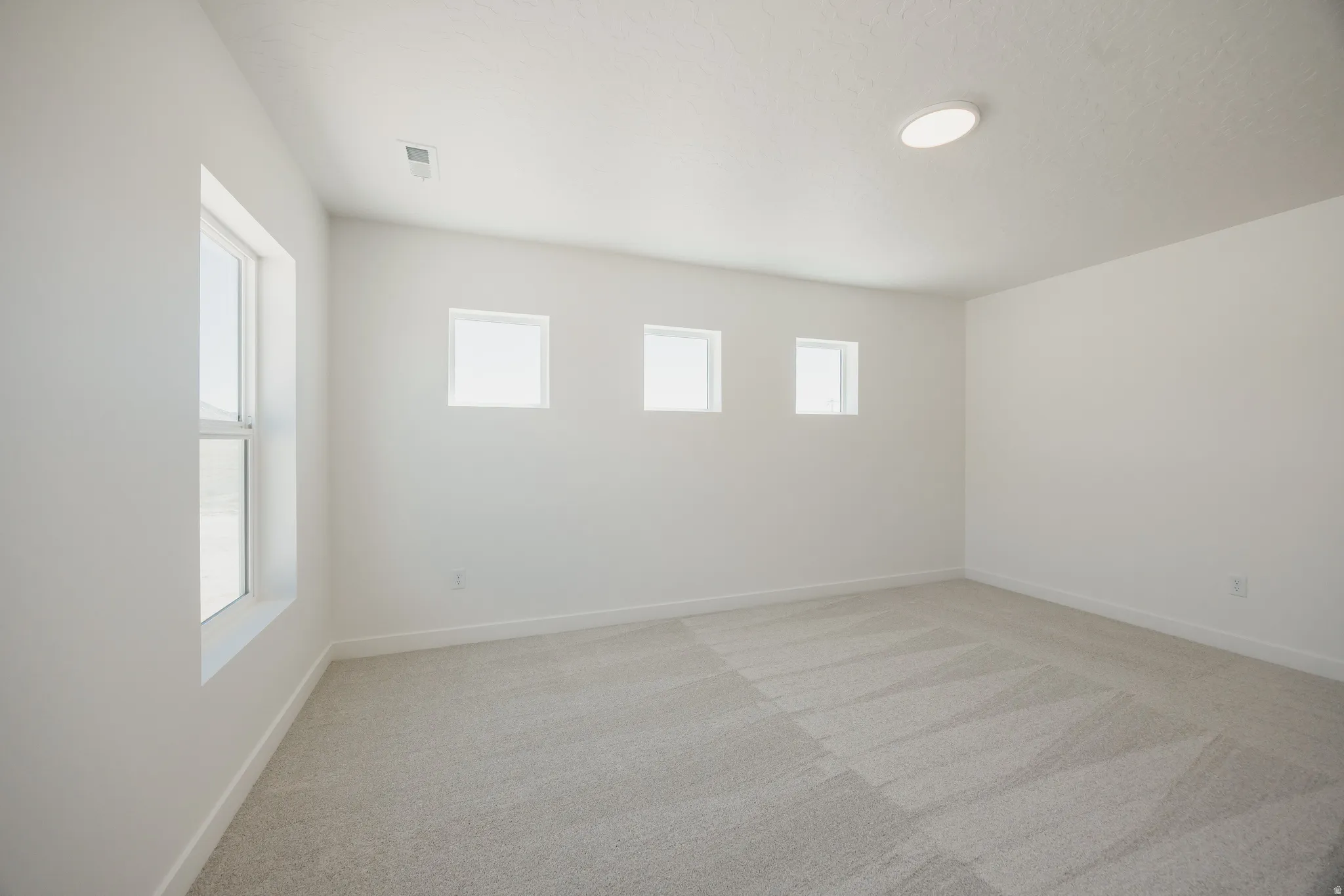 Spacious room featuring light-toned carpeting and neutral wall paint