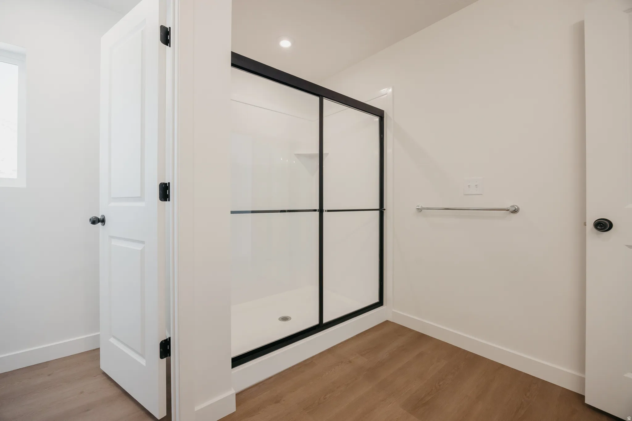 Contemporary shower enclosure featuring black-framed glass doors and a white shower base