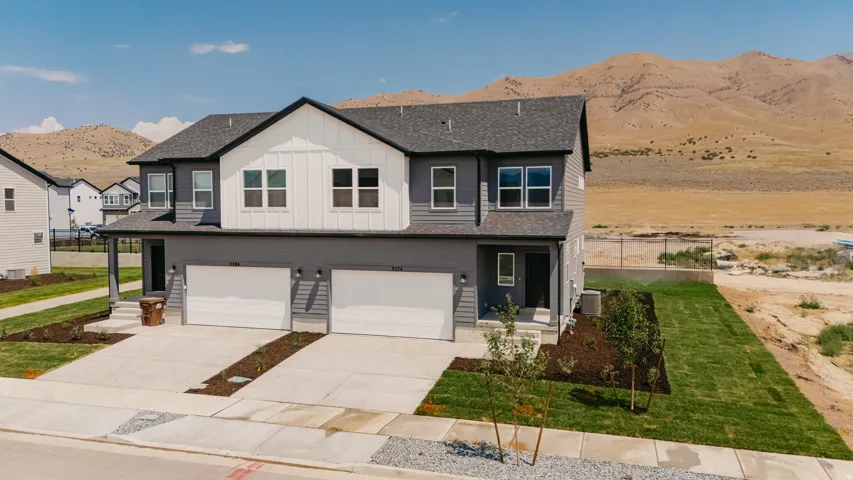 Two-story exterior with gray siding, white vertical accent panels, and a dark shingle roof