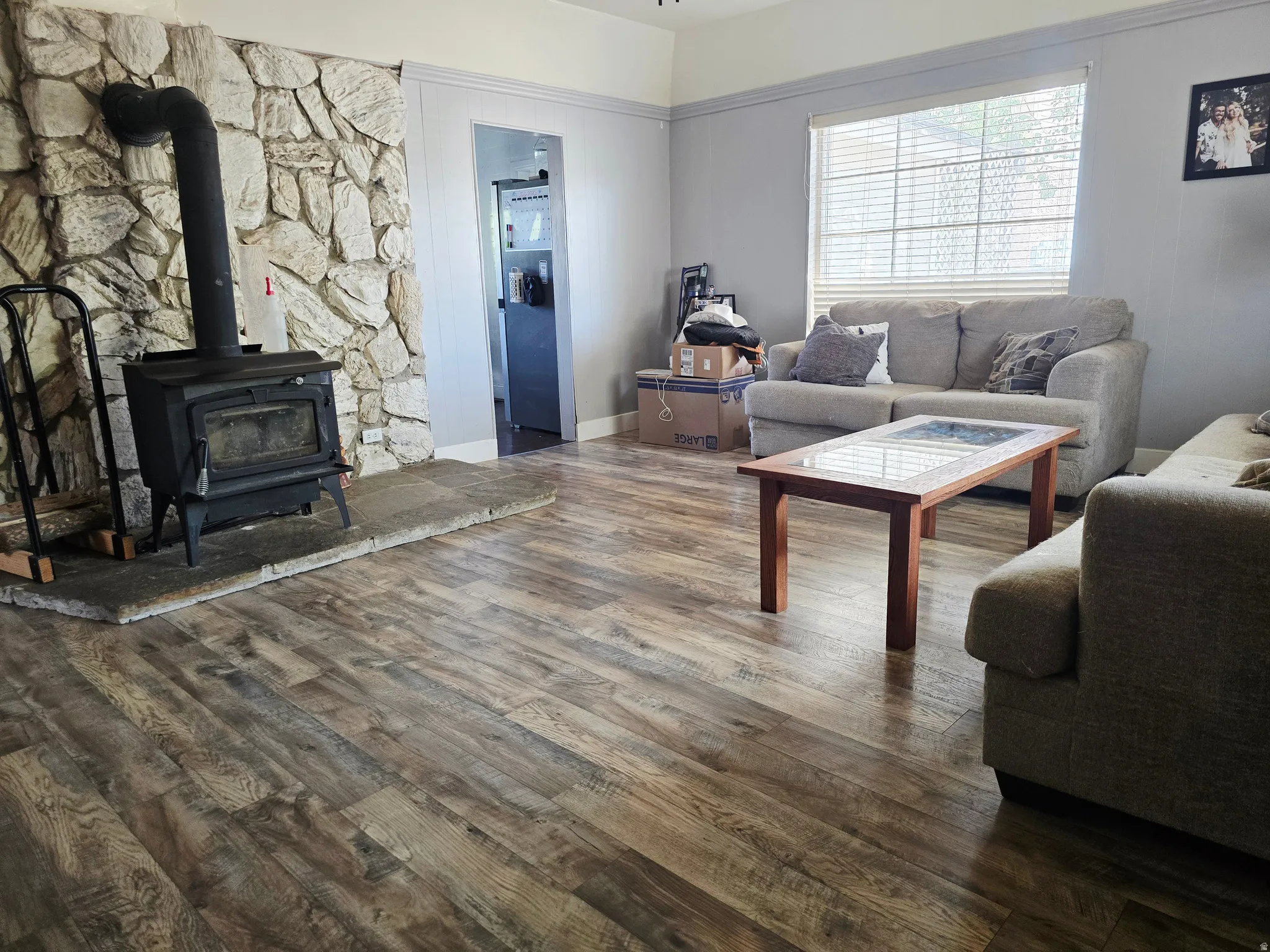Living area featuring a stone accent wall with a black wood-burning stove on a raised hearth