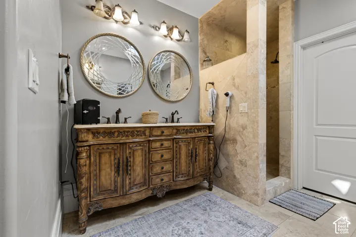 Bathroom featuring a carved wood-finish double vanity with dual sinks, stone countertop, and oil-rubbed bronze fixtures