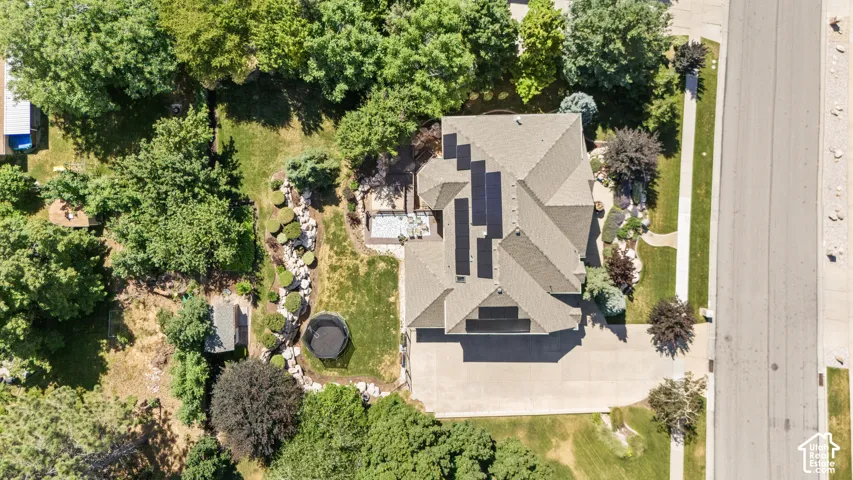 Aerial perspective showcasing a multi-gabled roofline with solar panels, a concrete driveway, and established landscaping
