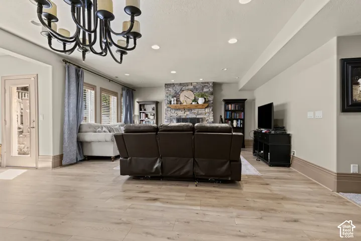 Spacious living area featuring wood-finish flooring, a stone fireplace with a wood mantle, and recessed lighting