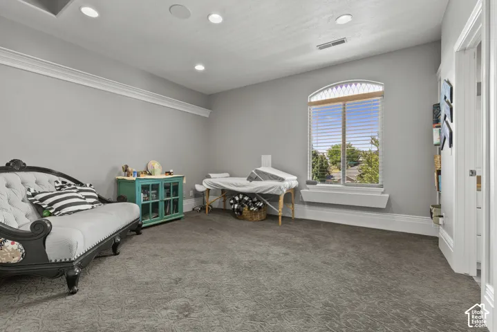 Spacious room featuring an arched window, recessed lighting, crown molding, and textured gray carpeting