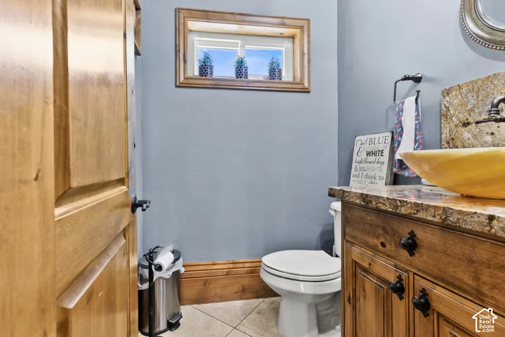 Powder room featuring a wood-finish vanity with dark hardware, a vessel sink, and a stone countertop