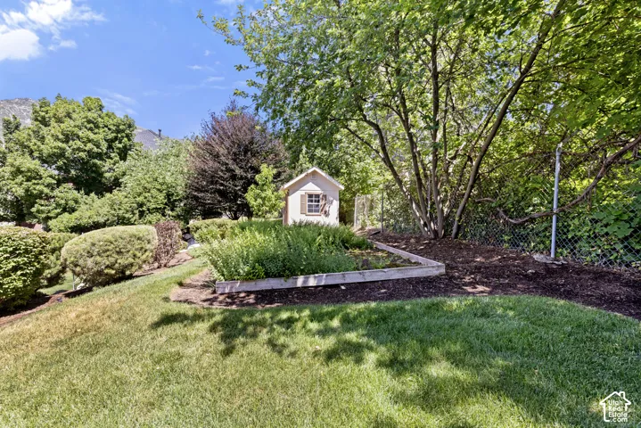 Expansive lawn area featuring a raised garden bed, mature trees, and a functional storage shed