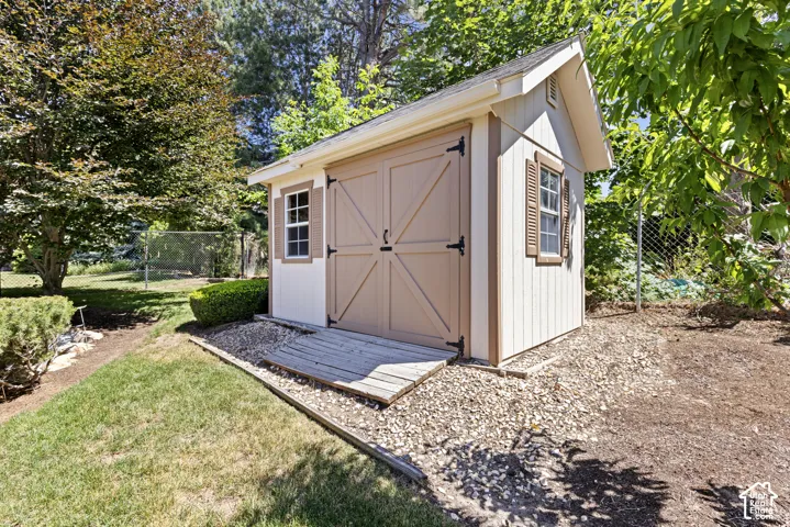 Detached shed featuring board-and-batten siding, double barn doors, and shuttered windows
