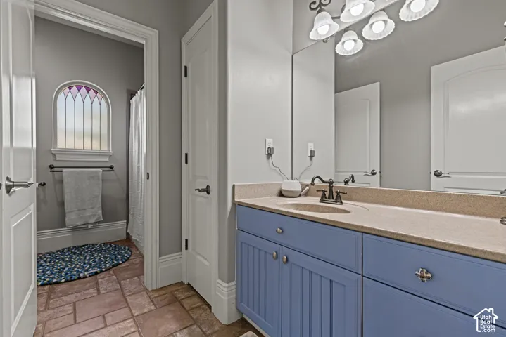 Bathroom featuring a blue shaker-style vanity with a light-colored countertop, an integrated sink, and an expansive mirror