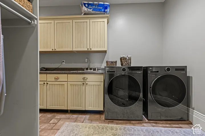 Dedicated laundry area featuring a utility sink, light-colored cabinetry, a dark countertop, and tiled flooring