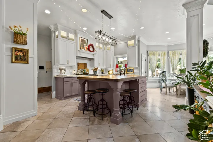 Expansive kitchen featuring a large central island with seating, white shaker-style upper cabinetry, contrasting lower cabinetry, recessed lighting, and diagonal tile flooring