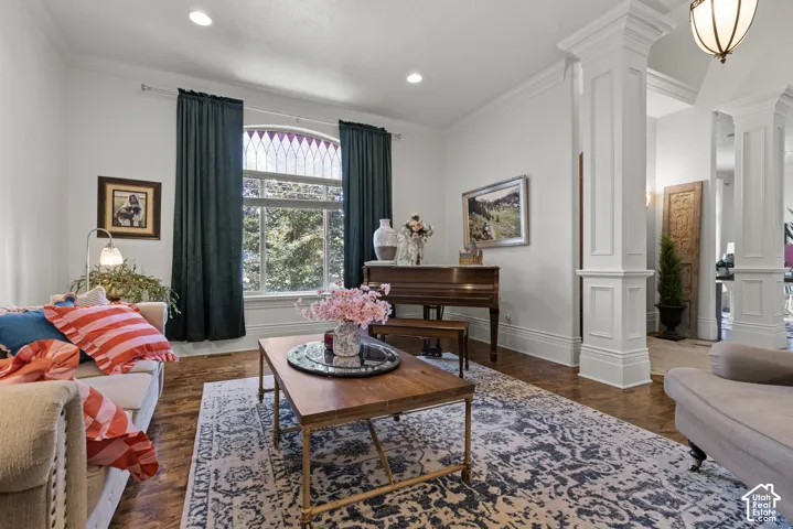 Living area featuring wood-finish flooring, white paneled columns, recessed lighting, and a large window with a decorative arched transom