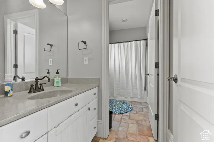 Bathroom vanity featuring a light-toned countertop with an integrated sink, white cabinetry with silver-toned hardware, and a framed mirror