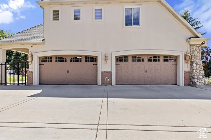 Stucco exterior featuring two garage bays with decorative wood-finish doors