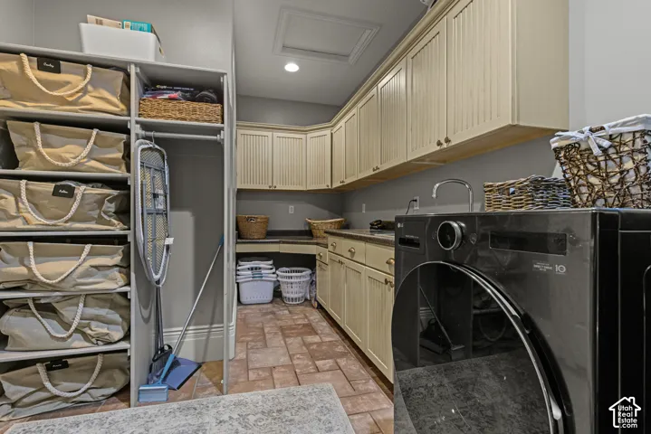 Utility room featuring ample cabinetry with beadboard paneling, integrated sink, stone-finish countertops, and durable tile flooring