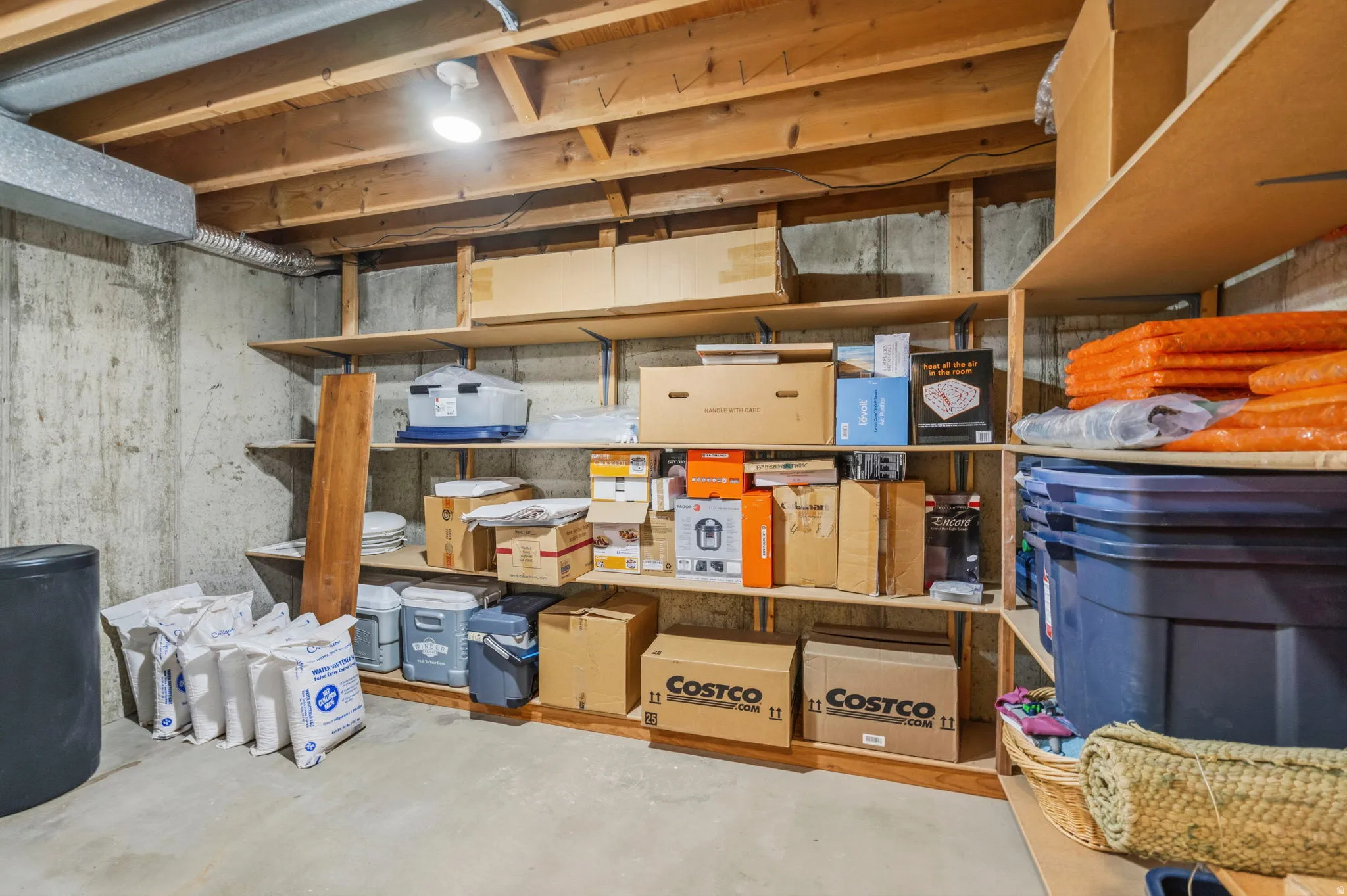 Basement unfinished storage area featuring extensive built-in shelving, concrete flooring