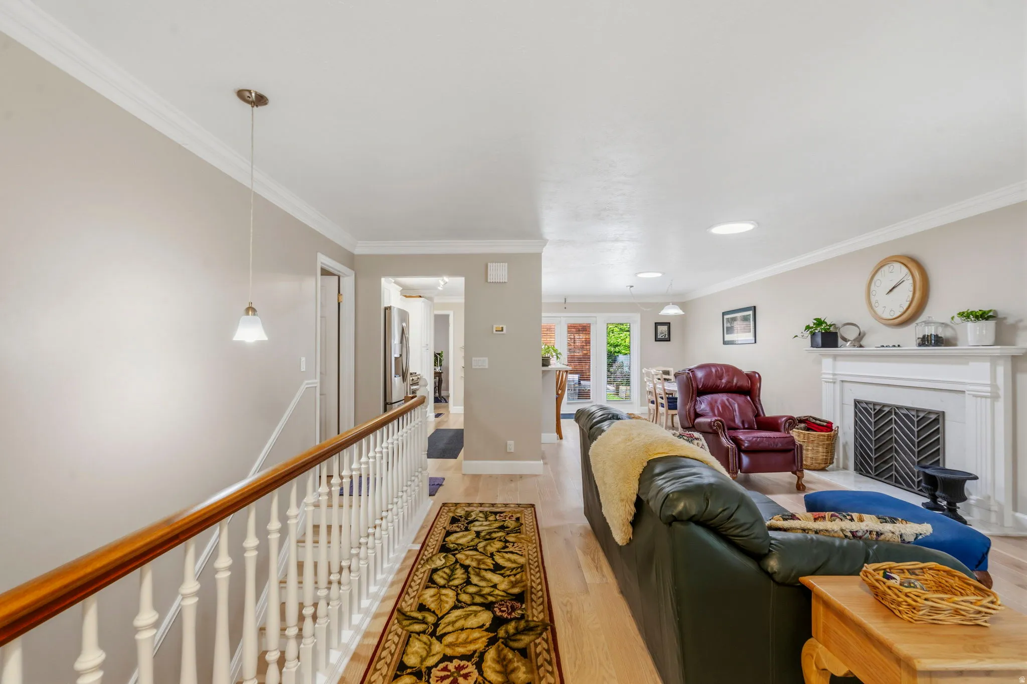 Spacious living area featuring white oak flooring, two-tone paint, solar tubes, lots of natural light, gas-log fireplace, and crown molding