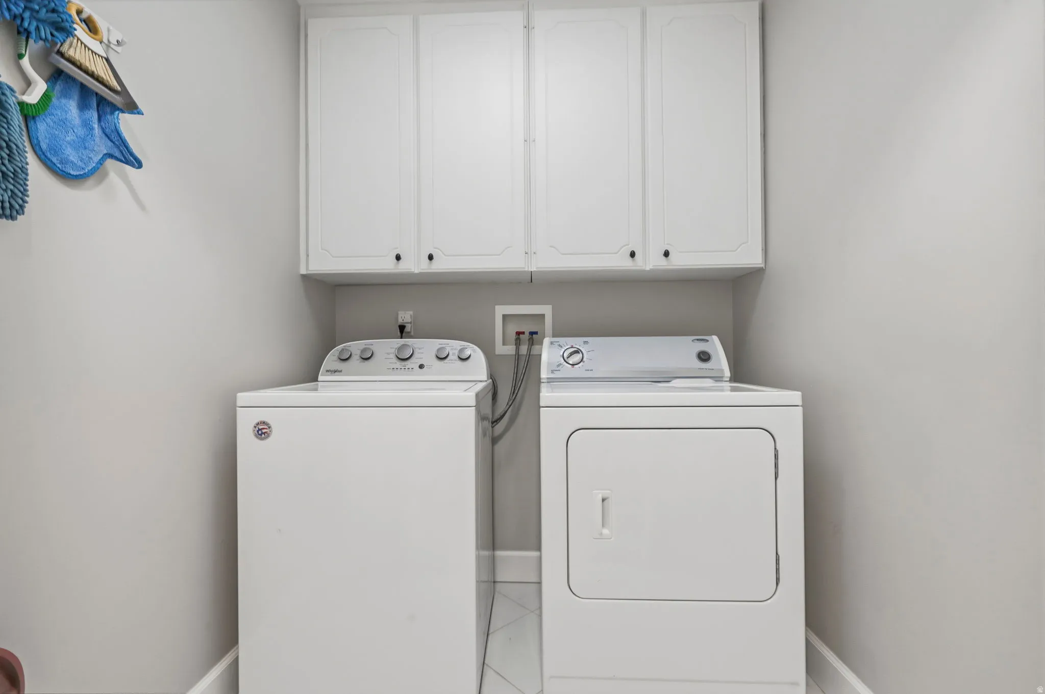 Dedicated laundry area with lots of overhead storage, tile floor.