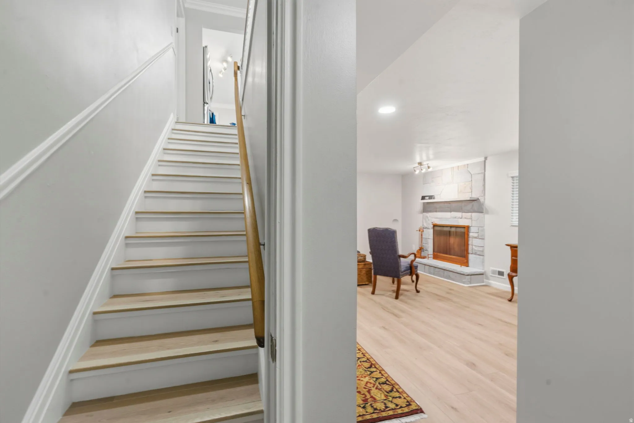 Stairwell featuring white oak treads, white risers, chair rail and a natural wood handrail