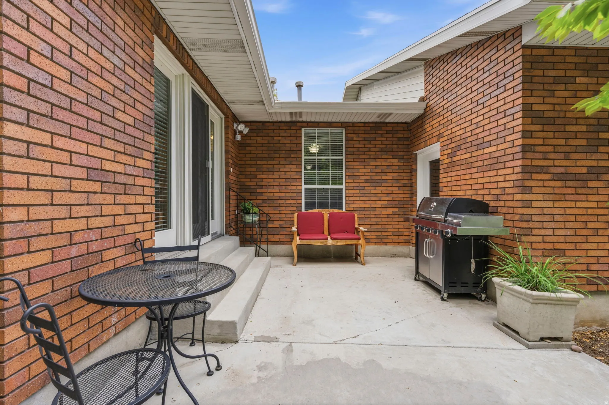 Concrete patio with brick exterior, featuring Anderson Atrium French doors, white window trim, and exterior lighting