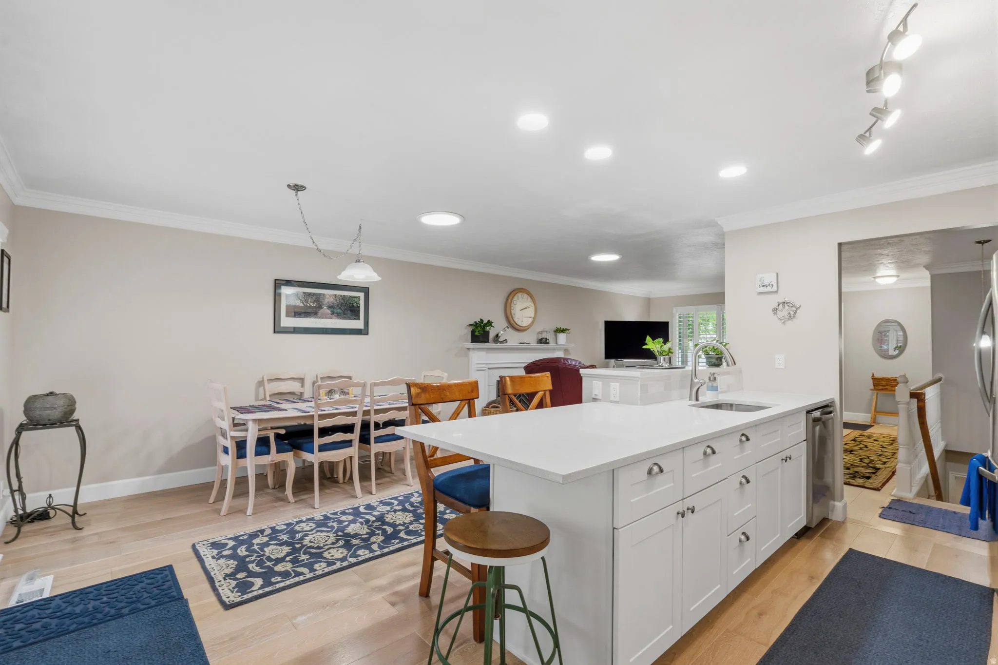 Open-concept kitchen featuring a large peninsula with white/gray speckled quartz countertops,undermount stainless sink, white shaker cabinetry with soft-close doors and drawers, stainless appliances and white oak floors