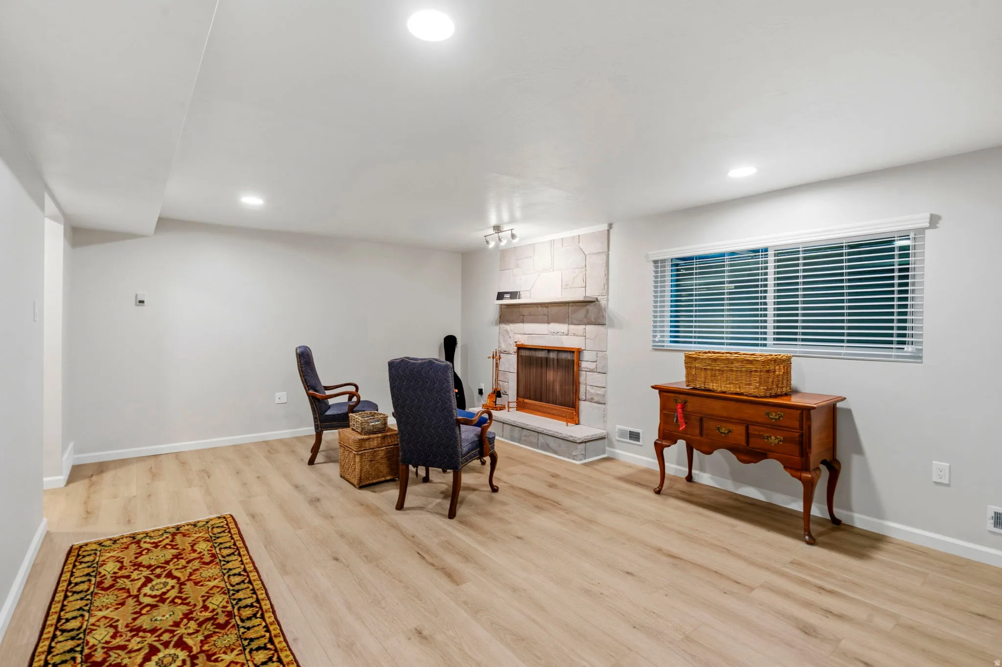 Spacious living area featuring LVP flooring, recessed lighting, and a stone-surround gas log fireplace with a stone mantel