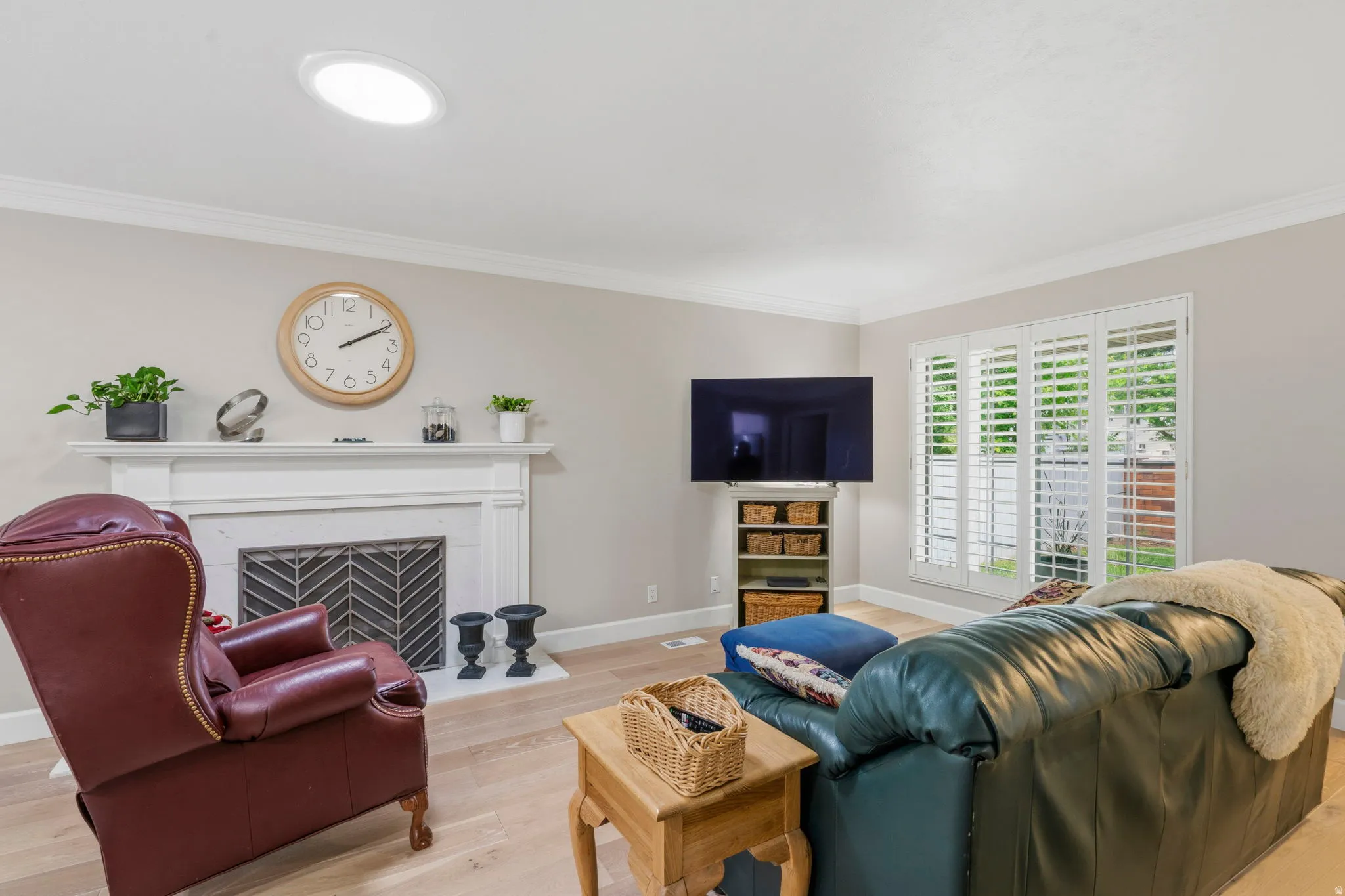 Spacious living area featuring white oak flooring, two-tone paint, solar tubes, lots of natural light, gas log fireplace, plantation shutters and crown molding