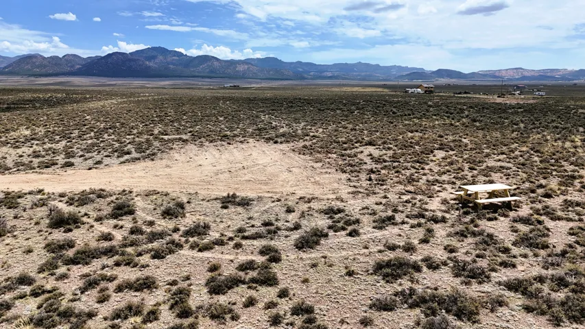 Expansive desert landscape featuring natural scrub brush and distant mountain ranges