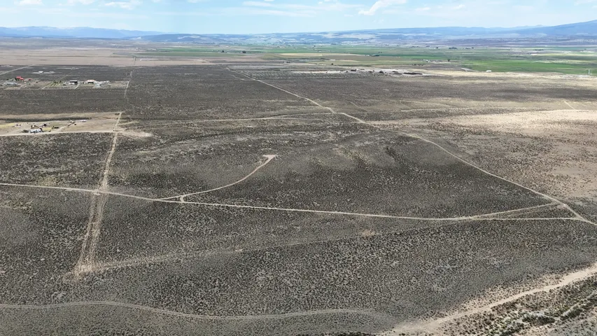 Expansive arid landscape featuring natural scrub vegetation and visible dirt paths