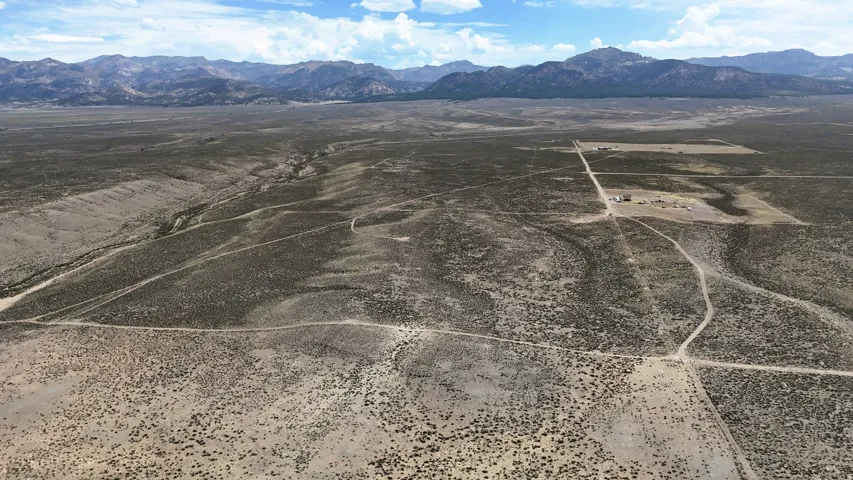 Expansive desert landscape featuring distant mountain ranges under a partly cloudy sky
