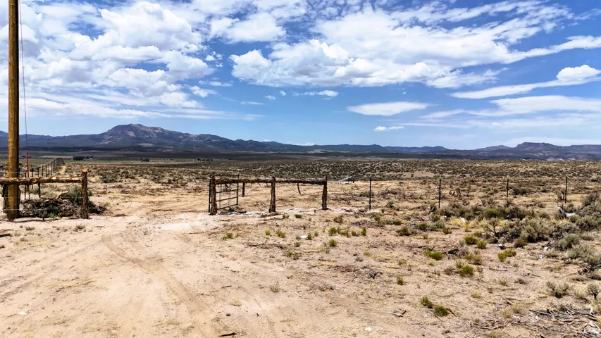 Expansive undeveloped land featuring a dirt access road and perimeter fencing