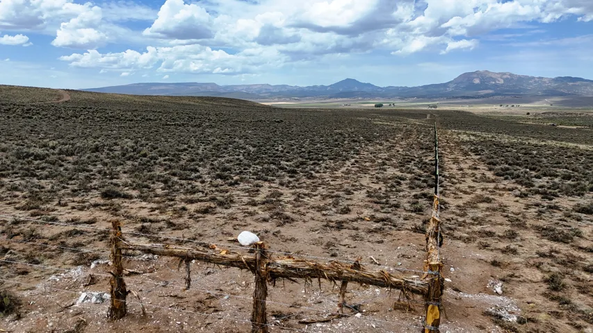 Expansive land parcel featuring open terrain and distant mountains under a partly cloudy sky