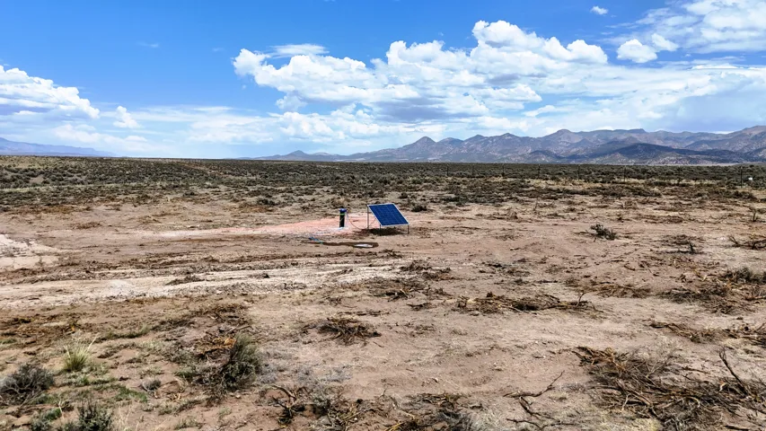 Expansive desert terrain featuring a solar panel installation and mountain backdrops