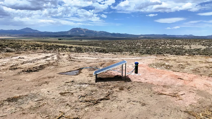 Expansive desert landscape featuring a solar panel installation and distant mountain ranges