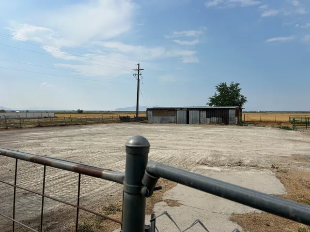 Gated entry to an expansive, unpaved lot with a corrugated metal 4 stall Barn