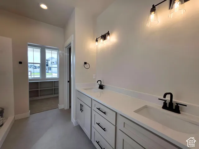 Dual vanity with white cabinetry and integrated sinks, matte black fixtures, and overhead lighting