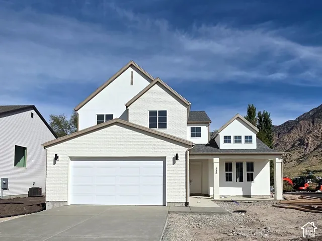 White stucco exterior with a two-car garage, covered entry, and a prominent mountain backdrop