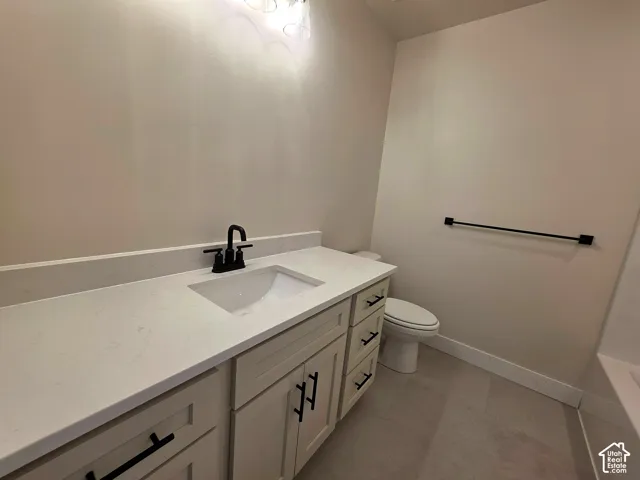 Vanity with integrated sink, matte black faucet, light cabinetry, and stone countertop